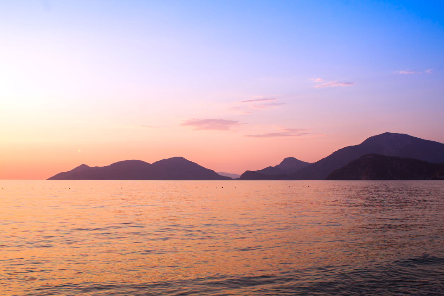 Tuerkei Urlaub-Sonnenuntergang am Meer mit Bergen am Horizont